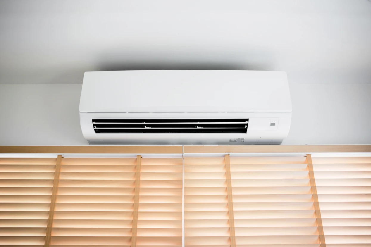 Intérieur résidentiel moderne avec climatiseur split mural blanc installé au-dessus de stores vénitiens en bois
