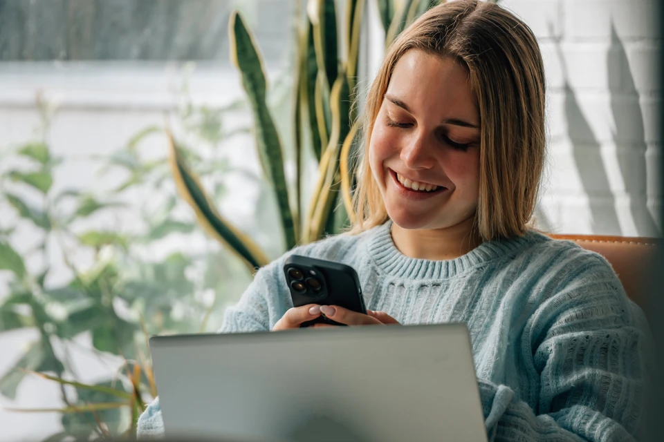 Un technicien chauffagiste/climaticien portant des vêtements de travail professionnels se tient devant un véhicule utilitaire blanc, regardant sa montre ou consultant son téléphone, montrant une attitude active et disponible. L'arrière-plan montre une rue résidentielle. L'image doit communiquer professionnalisme, urgence et réactivité sans artifice ni mise en scène forcée.